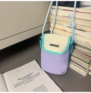 Detail view of a nylon crossbody phone bag with color-blocking design and braided strap