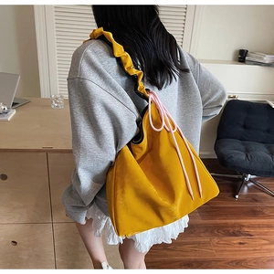 Détail d'un grand sac cabas jaune vif avec cordon rose et bandoulière à plis élégants