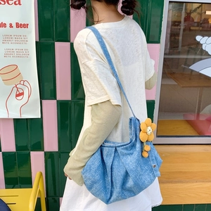 Détail d'un sac plissé en jean bleu orné d'une jolie breloque en forme de tournesol jaune