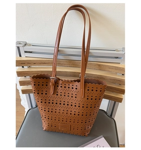 Close-up of laser-cut geometric patterns and scalloped edges on a brown faux leather tote