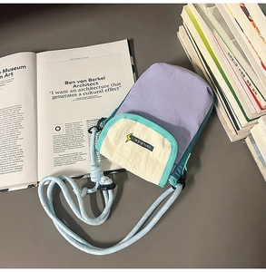 Detail of a purple nylon crossbody phone bag with color-block design and rope strap