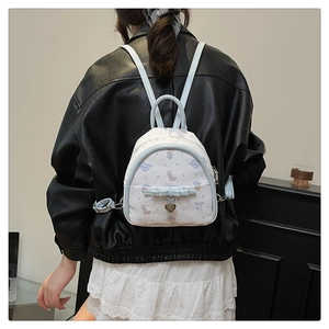 Gros plan d'un mini sac à dos blanc avec détails bleus et motifs lapins sur un mannequin