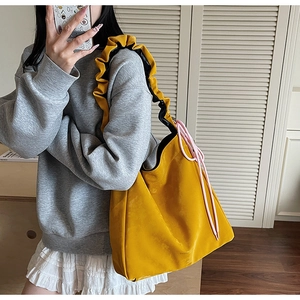 Detail of yellow tote bag featuring ruffled shoulder straps and pink drawstring contrast