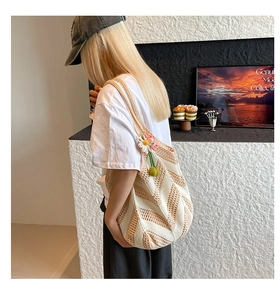 Detail of hand-woven striped crochet shoulder bag with floral charm decoration