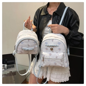 Détail d'un ensemble de deux sacs à dos crème avec motifs d'animaux mignons et nœuds bleus