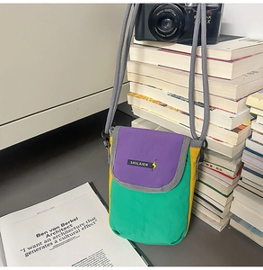 Detail view of a tricolor nylon crossbody bag with purple green and yellow stitching