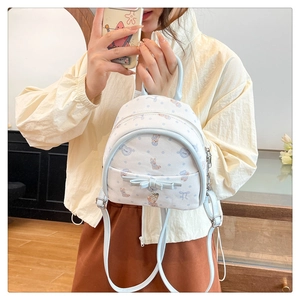 Détail d'un sac à dos blanc à pois bleus avec imprimé lapin et noeud décoratif