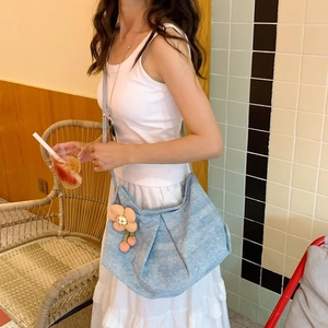 Gros plan du sac plissé en denim bleu clair avec décoration de fleur tricotée