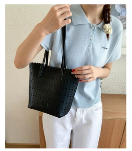 Detail of laser-cut hollow pattern and logo patch on black faux leather tote bag