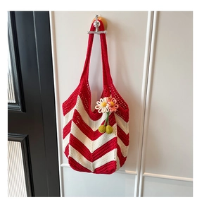 Detailed close-up of a handmade red and white woven crochet tote bag with a flower charm