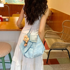 Détail du sac cabas en denim bleu clair avec breloque fleur orange dans un décor de café
