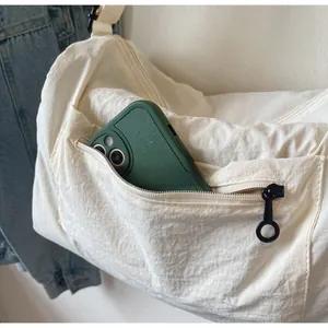 Close-up of front zipper pocket on nylon crossbody bag showing smartphone storage capacity