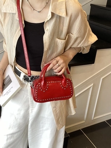 Red mini crossbody handbag with silver studs and top handles on a model