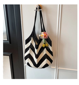 Close-up of black and white wavy crochet tote bag with decorative 3D floral pendant