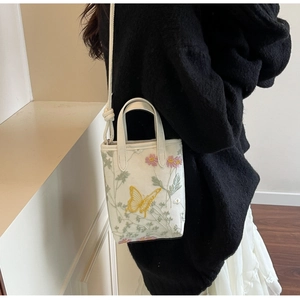Détail du sac cabas blanc orné de broderies colorées de papillons et de fleurs