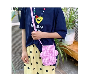 Dettaglio di una borsa a tracolla a forma di fiore a quadretti rosa e bianchi su un modello