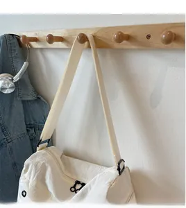 Detail of minimalist white canvas travel bag with adjustable strap and black metal hardware