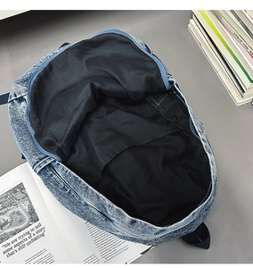 Detail of blue denim backpack interior showing black lining and inner pocket