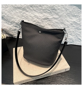 Détail d'un sac seau texturé gris foncé avec boucles argentées sur un livre