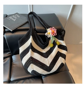 Detail of hand-woven knit tote bag featuring black and white waves and crochet flower charms
