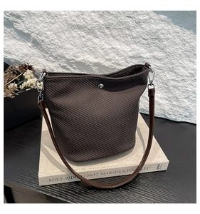 Détail du sac seau tressé marron foncé avec bouton pression argenté et sangle