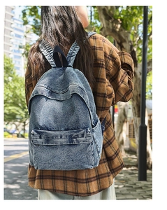 Outdoor shot of a vintage washed blue denim backpack with zipper pocket on a model