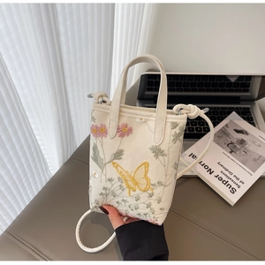 Détail du sac cabas beige brodé avec motifs floraux et papillons avec bandoulière réglable
