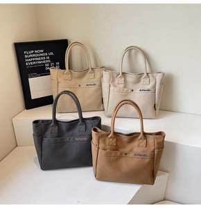 Detail of four canvas tote bags in beige, white, grey, and brown with front pockets