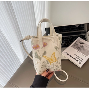 Détail du mini sac crème avec broderie florale champêtre et poignées élégantes