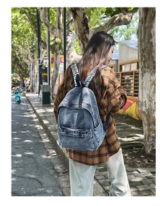 Detail of vintage blue denim backpack showing wash texture and front zipper pocket