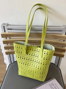 Neon yellow laser-cut hollow tote bag with wavy edges and adjustable shoulder straps