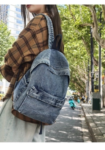 Outdoor shot showing side view of washed blue denim backpack for travel and daily use