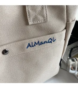 Close-up of canvas tote bag with AlManQi embroidery and metal rivet reinforcements