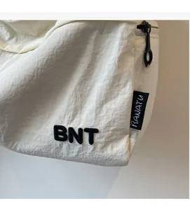 Close-up detail of white nylon shoulder bag featuring BNT embroidery and wrinkled texture
