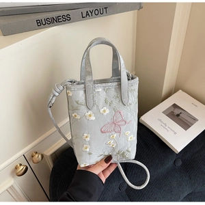 Détail du sac cabas gris clair avec broderies délicates de papillons et fleurs de style