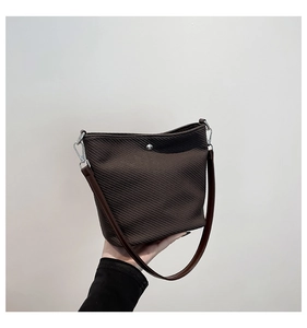 Détail du sac seau marron foncé avec texture tissée et boucles métalliques argentées