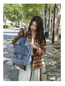 Detailed view of vintage washed blue denim backpack with large front zipper and top handle