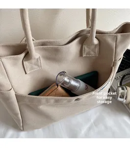 Detail of beige canvas tote bag showing the functional large front pocket for storage