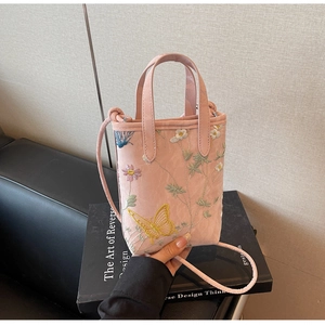 Détail d'un sac cabas rose brodé avec des motifs floraux et des motifs de papillon