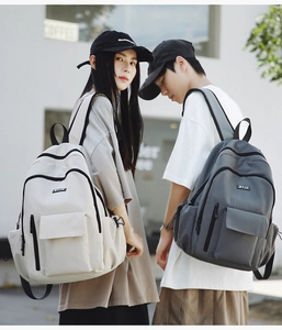 Detail of large canvas backpacks in beige and grey with flap pockets for travel and school