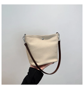Détail du sac seau tissé crème avec bandoulière marron et fermoirs en argent