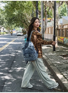 Detail of vintage washed blue denim backpack with striped woven straps in outdoor street setting