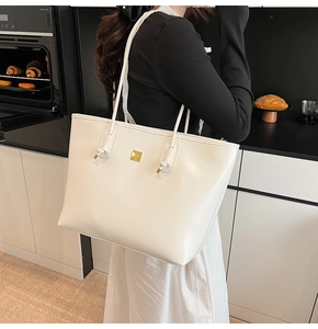 Detail of white PU leather tote bag with gold logo on a modern kitchen background