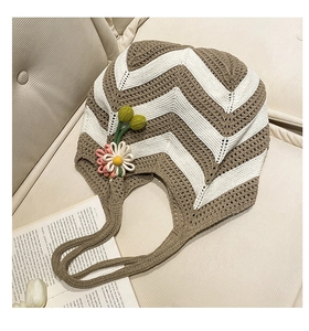 Detail of woven tote bag with brown wave patterns and 3D knitted flower decorations