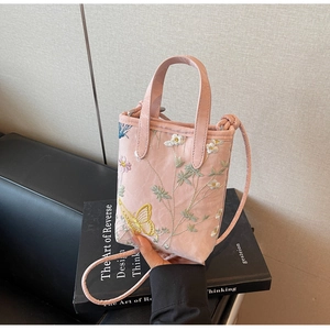 Gros plan détaillé du sac cabas rose clair avec broderie fleurs et papillons