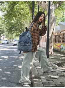 Outdoor view of a vintage blue washed denim backpack with large capacity worn by a model