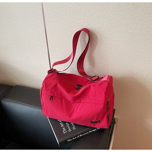 Close-up of red nylon crossbody bag featuring BNT embroidery and multiple zippers