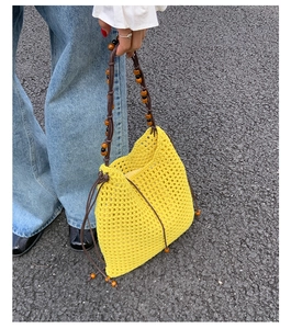 Details einer gelben gehäkelten Netztasche mit Holzperlengriffen und seitlichen Kordelzügen