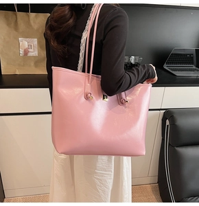 Detail showing pink leather tote bag with slim shoulder straps and gold metal hardware