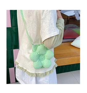 Dettaglio mini borsa a tracolla a forma di fiore a quadretti verdi indossata da modella